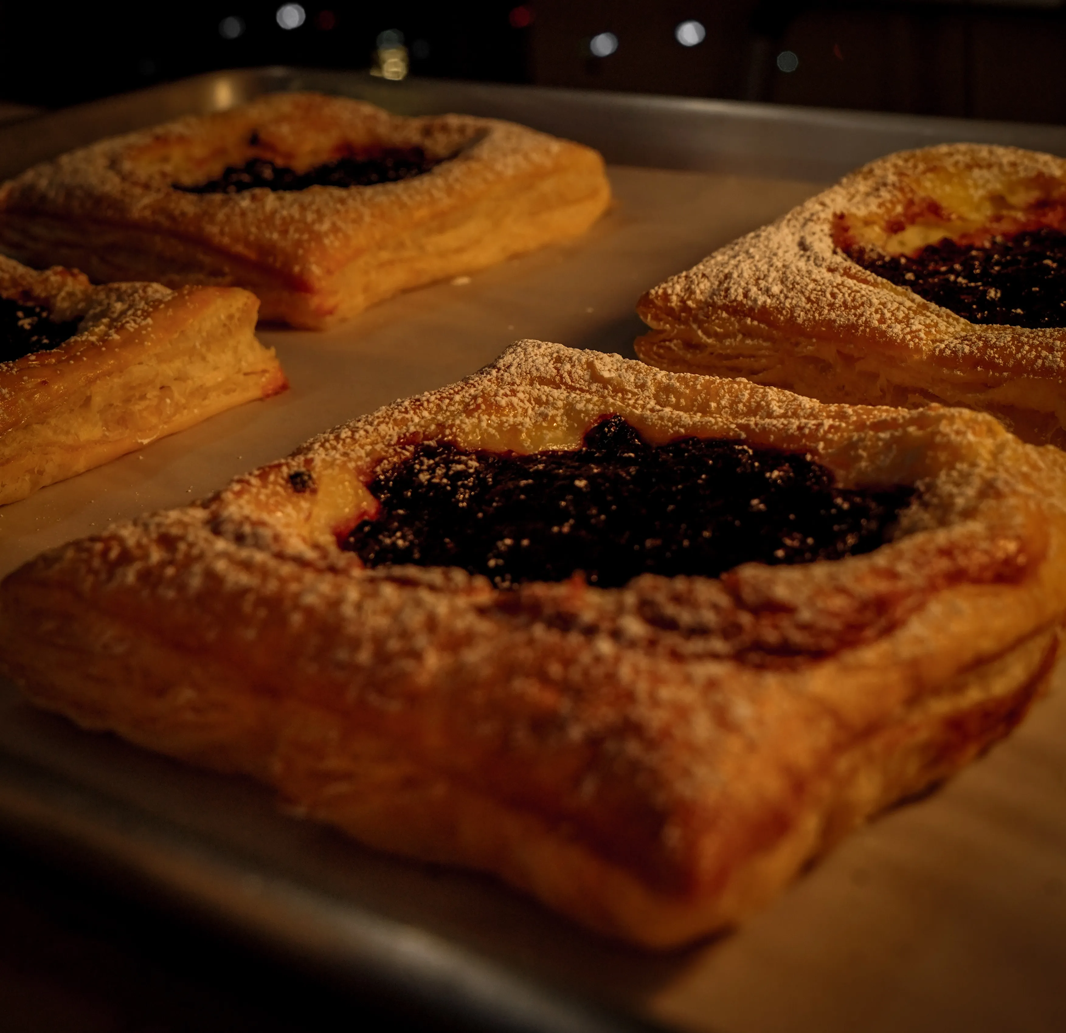 Fresh berry pastries with powdered sugar on a baking sheet